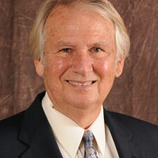 A man in suit and tie smiling for the camera.